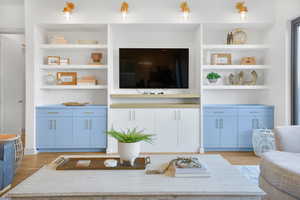 Living area with built in shelves and light wood-style floors