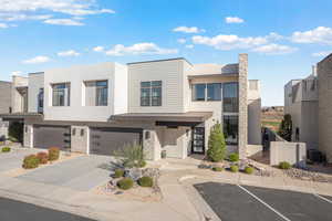Contemporary home featuring stone siding, stucco siding, a garage, a standing seam roof, and concrete driveway