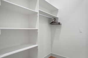 Walk in closet with dark wood-style flooring