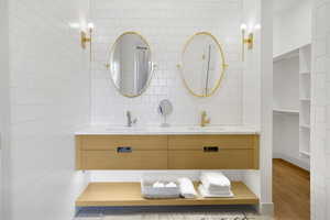 Bathroom featuring double vanity, tile walls, and a spacious closet