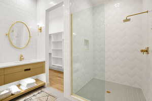 Full bathroom featuring tile walls, vanity, walk in shower, a spacious closet, and built in shelves