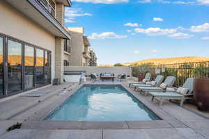 View of pool featuring a hot tub, patio surround, a fenced backyard, and an outdoor living space