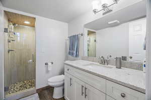 Downstairs: Full bath with vanity, a shower stall, and dark wood-style floors