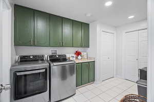 Laundry area with washer and clothes dryer, light tile patterned floors, cabinet space, and recessed lighting