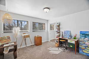 Downstairs: Office space with baseboards and light colored carpet