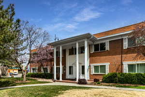 Greek revival inspired property with brick siding, a front yard, and covered porch