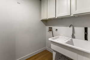 Laundry area featuring light wood finished floors, hookup for a washing machine, and cabinet space