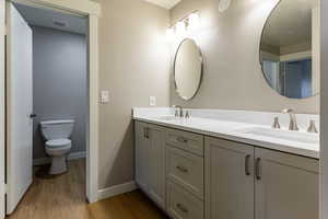 Bathroom with double vanity and light wood-style flooring