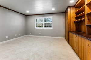 Empty room with ornamental molding, light colored carpet, and recessed lighting