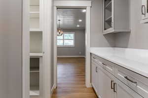 Hallway featuring light wood-type flooring, ornamental molding, and hanging lights