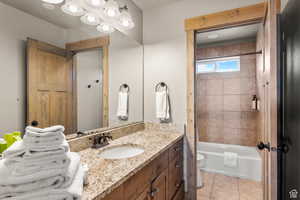 Bathroom featuring vanity, shower / tub combination, and light tile patterned flooring