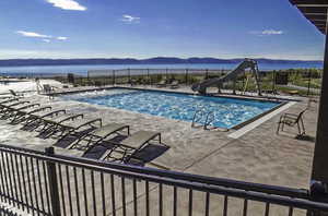 Community pool with a mountain view, a patio area, and a water slide