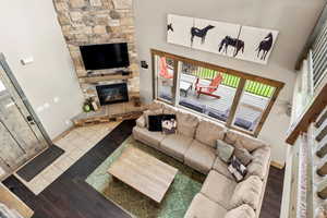 Living room with a stone fireplace, light wood-style floors, and a high ceiling