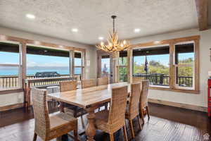 Dining area with dark wood finished floors, a chandelier, and a textured ceiling