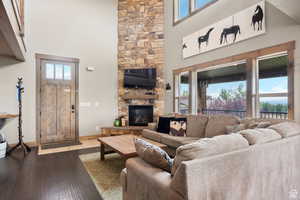 Living area with a high ceiling, hardwood / wood-style flooring, and a stone fireplace