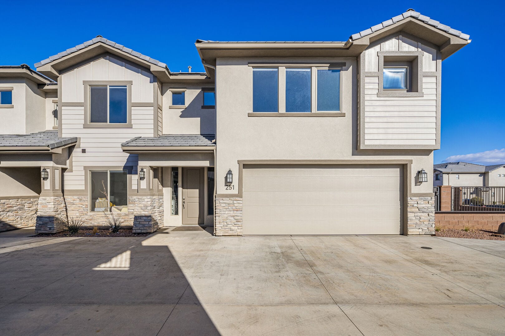 View of front of house featuring stone siding, a garage, concrete driveway, and stucco siding