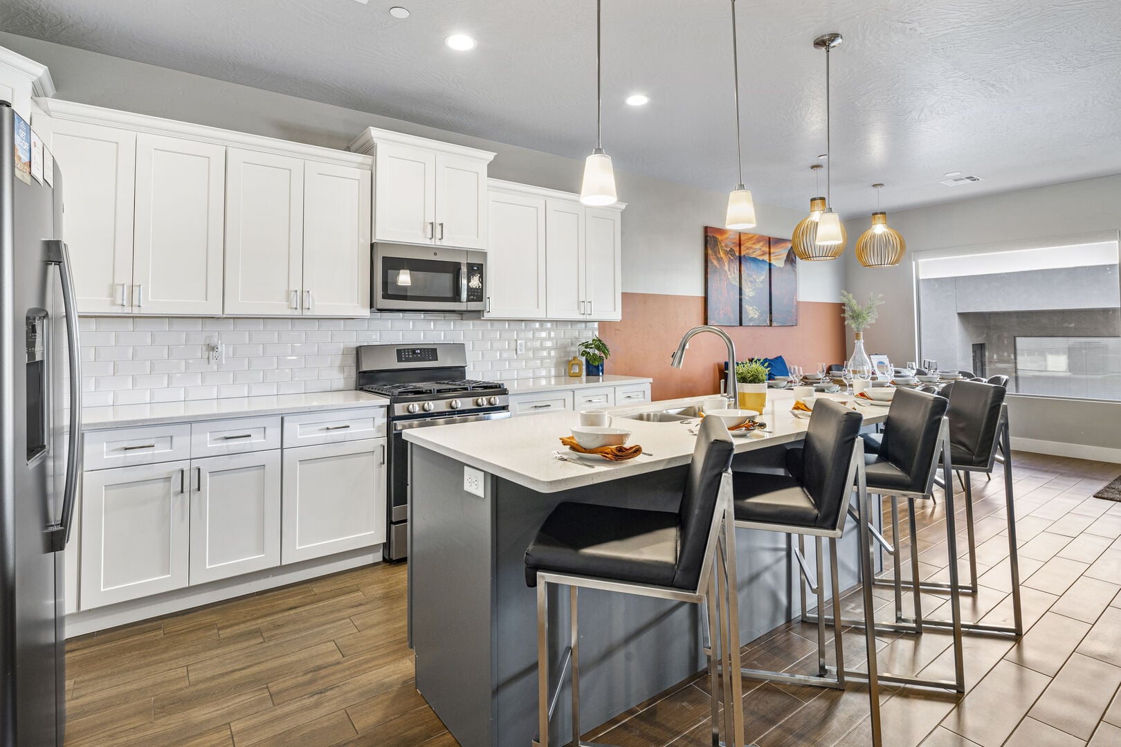Kitchen with two tone color scheme, stainless steel appliances, a kitchen island with sink, dark wood-type flooring, and a breakfast bar area