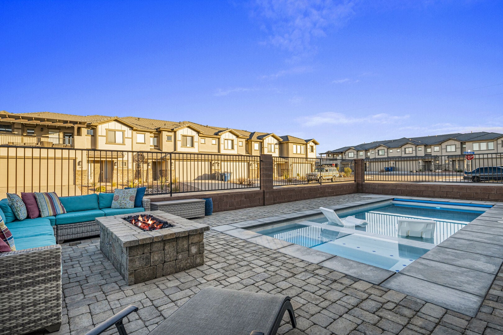 View of swimming pool featuring patio surround, a residential view, an outdoor living space with a fire pit, and a hot tub
