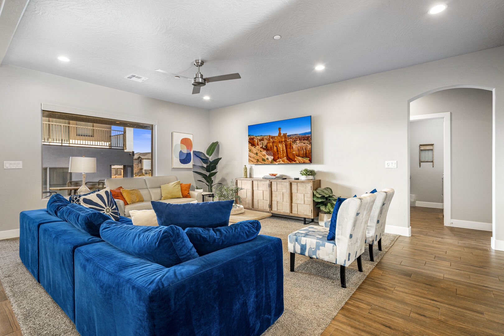 Living room with a ceiling fan, arched walkways, wood finished floors, and recessed lighting