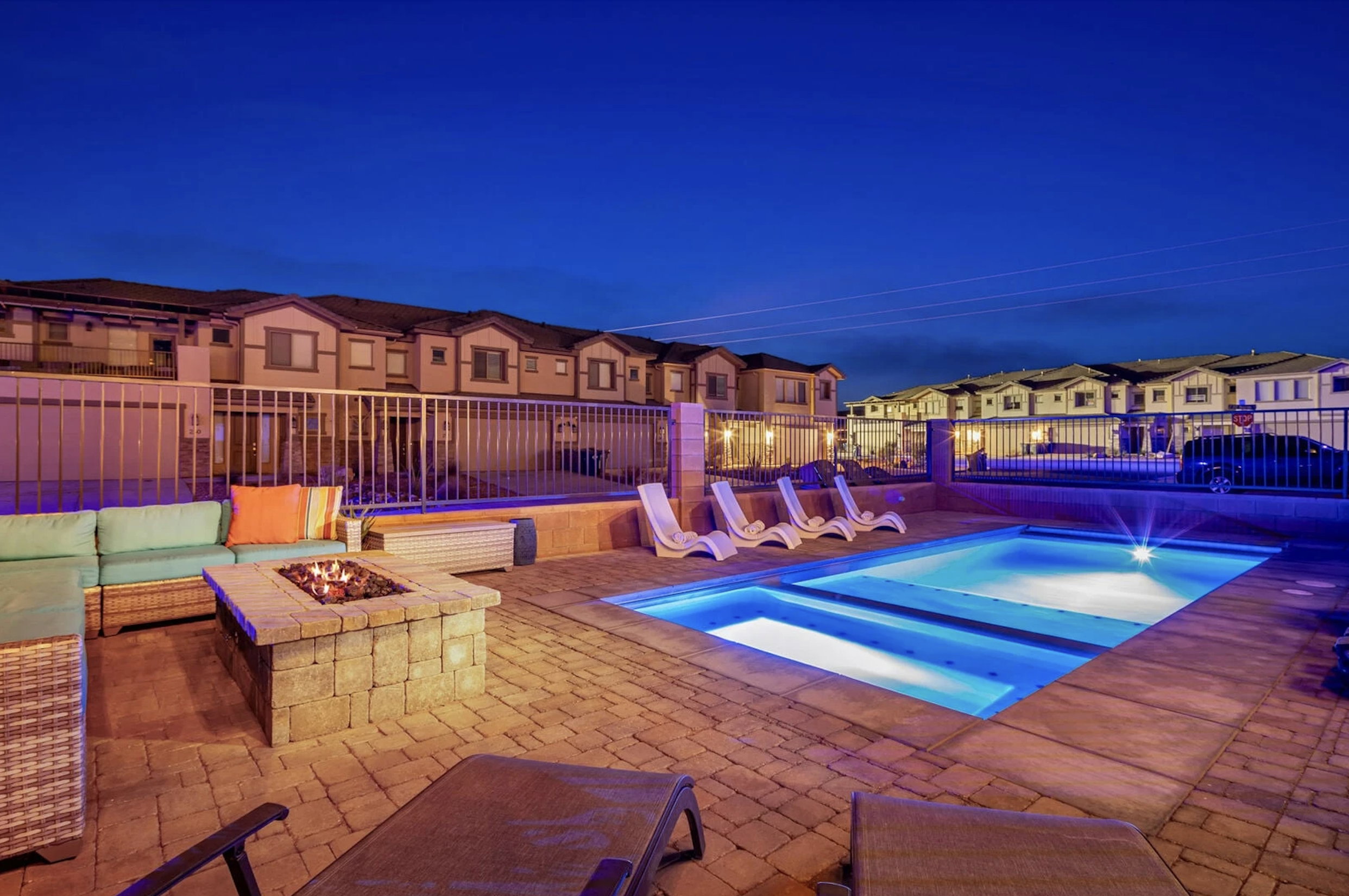 View of pool with a residential view, an outdoor fire pit, patio surround, and a hot tub