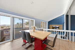 Dining area featuring lofted ceiling, light wood finished floors, an accent wall, and recessed lighting