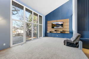 Sitting room with vaulted ceiling and carpet flooring