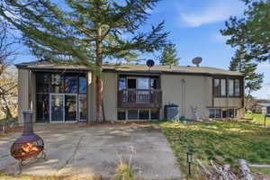 Back of property featuring an outdoor fire pit, a sunroom, a lawn, and a patio area