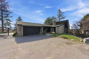 Mid-century modern home with a garage, asphalt driveway, and a shingled roof
