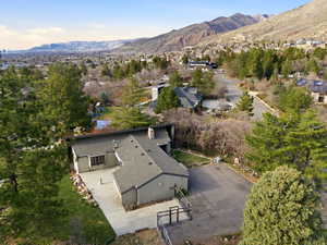 Aerial view of property and surrounding area featuring mountains and a tree filled landscape