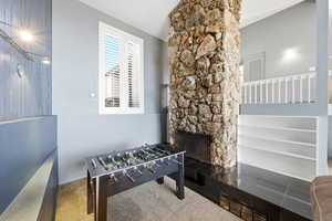 Game room with a stone fireplace and lofted ceiling