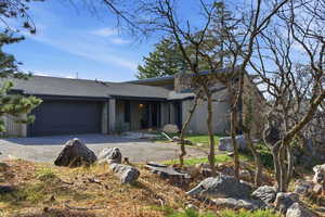View of front of property featuring roof with shingles, an attached garage, driveway, and a patio area