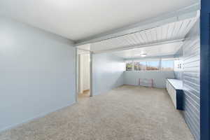 Empty room with light carpet and beam ceiling
