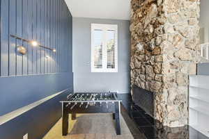 Recreation room with carpet flooring, an accent wall, and wood walls