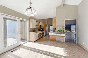 Kitchen featuring light countertops, stainless steel appliances, lofted ceiling, light tile patterned floors, and suspended lighting