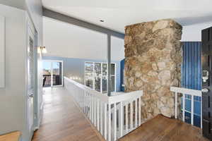 Hallway featuring wood finished floors and vaulted ceiling