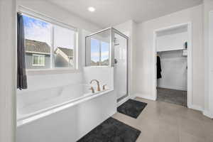 Primary bath with a separate shower, a walk in closet, a garden tub, and light tile patterned floors