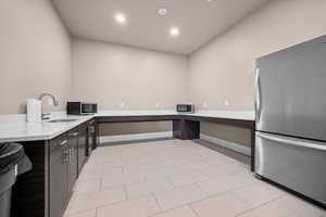 Clubhouse kitchen with freestanding refrigerator, modern cabinets, light stone countertops, dark wood finish cabinetry, and recessed lighting