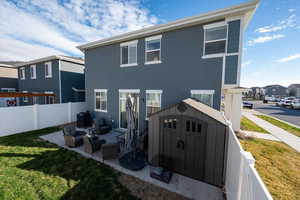 Rear view of house with a storage shed, stucco siding, and a patio