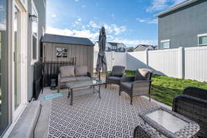 Fenced backyard featuring a patio, a gate, a residential view, and a storage shed