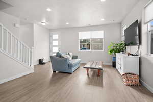 Living room featuring light wood-style floors, recessed lighting, and a textured ceiling
