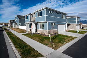 View of front facade with stone siding, a garage, driveway, and a residential view