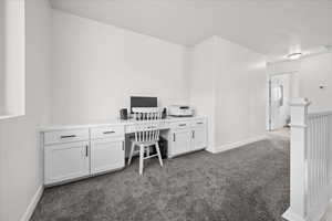 Office featuring dark colored carpet and a textured ceiling