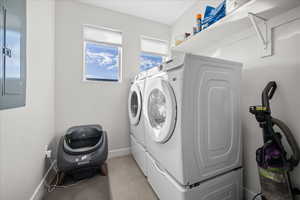 Laundry area featuring electric panel, independent washer and dryer, and light tile patterned floors