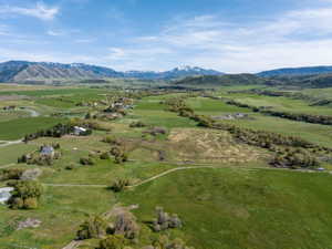 Expansive rural landscape featuring a mountainous backdrop with snow-capped peaks