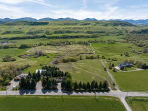 Expansive property featuring verdant fields, a distant mountain range, and a residential structure with an attached garage