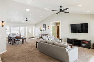 Living area with a ceiling fan, light colored carpet, recessed lighting, and a high ceiling