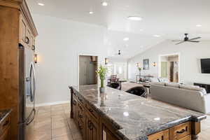 Kitchen with open floor plan, dark stone counters, stainless steel fridge with ice dispenser, recessed lighting, and a high ceiling