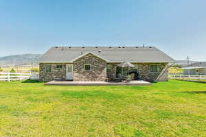 Back of property with a mountain view, brick siding, a patio area, and a shingled roof