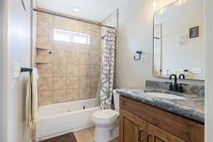 Bathroom with vanity, shower / bath combination with curtain, and light tile patterned floors