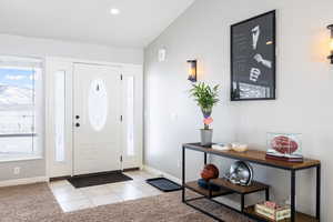 Entrance foyer featuring lofted ceiling, light tile patterned flooring, recessed lighting, and light carpet